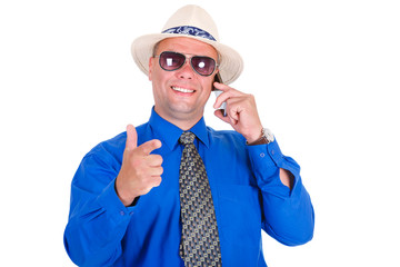 Successful and smiling businessman in jeans, blue shirt, tie, sunglasses and white hat. Speaking by cell mobile phone and shows the index finger. Isolated white background, Concept of leadership