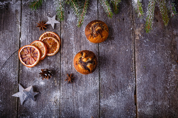 Xmas or new year composition with holiday decoration - Homemade christmas cupcakes on wooden background with spruce twigs and pinecones. Christmas card. Space for text