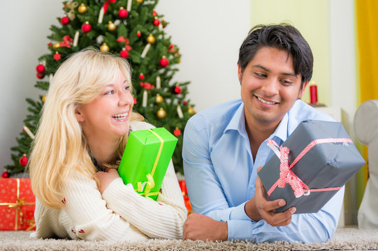Nettes Ehepaar hat Spass beim öffnen der Weihnachtsgeschenke