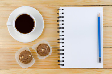 Obraz na płótnie Canvas A blank white notebook and cup of coffee and pencil with cookie on the wooden table