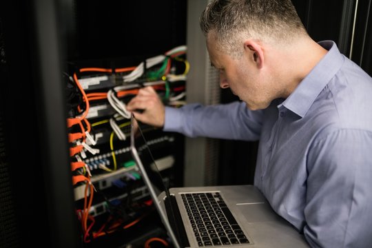 Technician looking at open server locker while holding a laptop