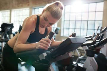 Fit young female exercising on gym bike