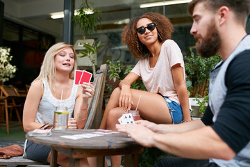 Group of young people playing cards at cafe
