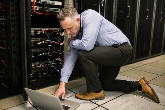 Technician using laptop to analyse server