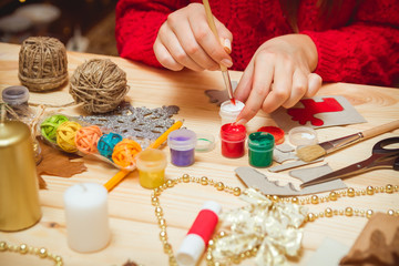 The girl at the table makes Christmas gifts. Hand made