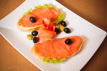 Salmon on a bread with salad and olives