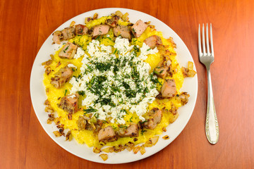 Polenta with meat and homemade cheese on plate, top view