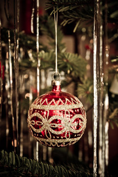 Rot glänzende Christbaumkugel mit goldenem Muster am Weihnachtsbaum