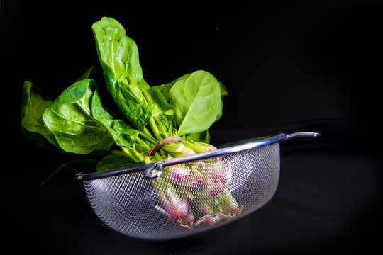 Manojo de espinacas frescas aisladas sobre un fondo negro, vegetales para una comida sana
