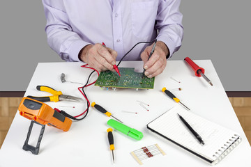 Electronic test engineer using a multimeter to test a circuit board