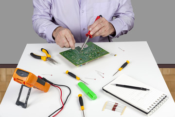 Electronic test engineer using a soldering iron on a printed circuit board