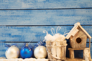 Birdhouse and Christmas decoration on blue background.