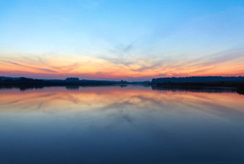 Fototapeta na wymiar Sunset landscape with blue sky at the calm lake
