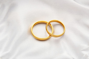 Golden wedding rings on a white satin