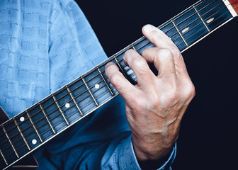 Left hand of musician, guitarist playing chord on acoustic guitar fingerboard
