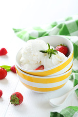 Ice cream in bowl with strawberries and raspberries on white woo