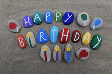 Happy Birthday message on colored stones over the sand