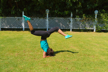Young woman doing handstands at the park in summer.