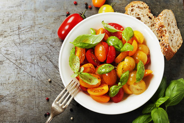 Fresh tomatoes with basil leaves in a bowl