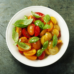 Fresh tomatoes with basil leaves in a bowl
