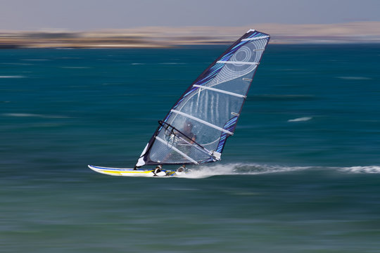 Windsurfen in Ägypten, Hurghada. Mann surft im Meer mit blauem Segel.
