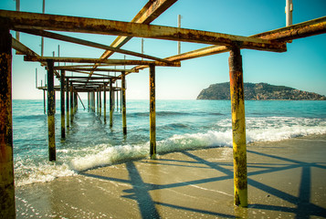 Metal pier on the beach and beautiful view to ancient fortress o
