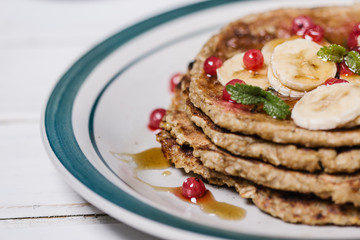 Stack of healthy low carbs oat pancakes over white wooden background