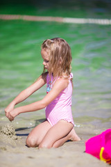 Adorable little girl playing with beach toys during tropical vacation