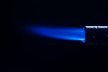 Single intense gas jet flame of industrial gas-burner against a black background 