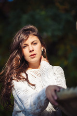 Two happy and cheerful young girl students, blond and brunette in coat and jeans laughing in sunny autumn park full of fallen leaves, horizontal pictures
