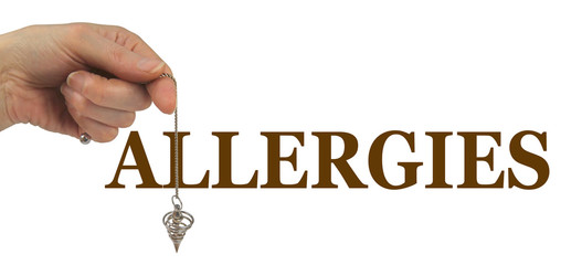 Using a Dowsing Pendulum to detect Allergies - female hand holding a silver spiral dowsing pendulum with the chain breaking through the L of the word ALLERGIES on a white background