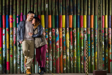 Obraz na płótnie Canvas Affectionate young couple standing in front of the colorful wooden wall