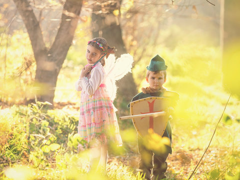 Cute little children dressed up as a knight and a fairy walking in the woods