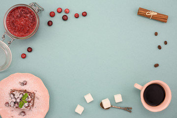 Coffee and chocolate cake with cranberry jam and cinnamon on wooden board, over turquoise background. Top view, copy space.