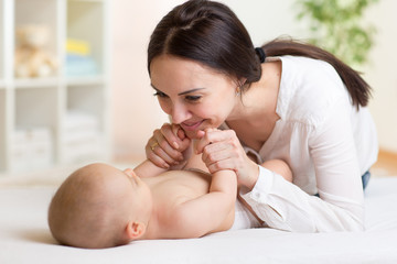 Happy mother playing with her baby in bedroom