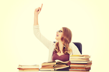 Young woman with books pile pointing up