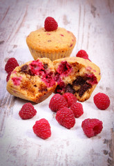 Fresh baked muffins with chocolate and raspberries on wooden background, delicious dessert