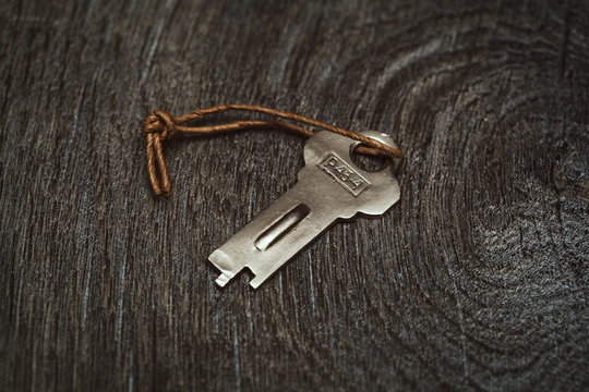 decorative vintage key on a rope on a wooden textured board