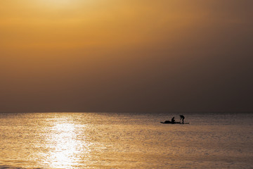 Naklejka na ściany i meble Golden sunset with fisherman boat