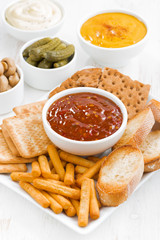 assortment breads, crackers and sauces on white table