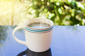 Classic white cup of black coffee  with tree background
