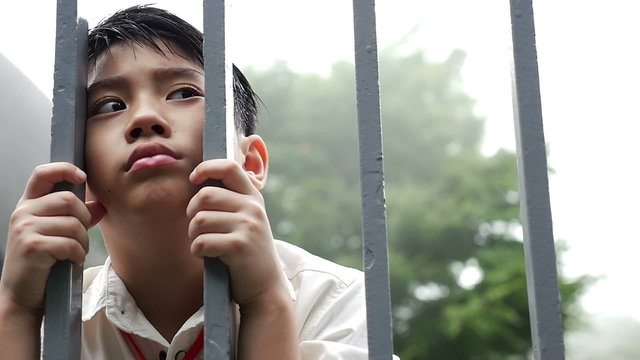 Sadness Asian boy be hide the fence, Pan shot