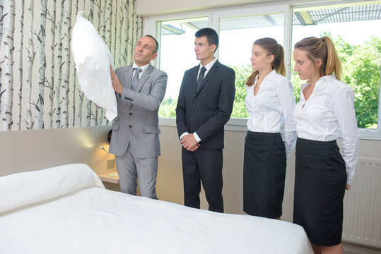 Hotel staff watching supervisor with pillow
