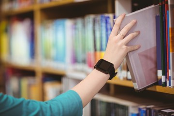 Students hand with smartwatch picking book from bookshelf © WavebreakmediaMicro