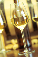 Wineglass of white wine in front of bottle