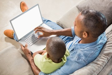 Father and son using laptop on the couch