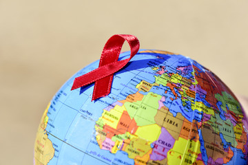 world globe with a red ribbon for the fight against AIDS - obrazy, fototapety, plakaty