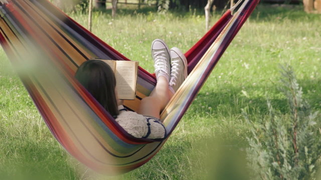 Girl in hammock reading a book - wide shot
