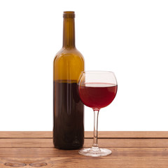 Glass and bottle of red wine unusually on wooden background.