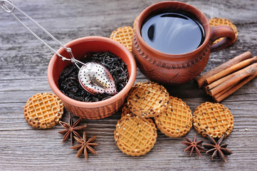 A cup of hot tea with cookies on a rustic wooden background